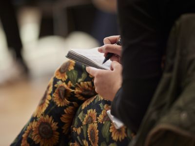Participant taking notes in a notebook on her lap